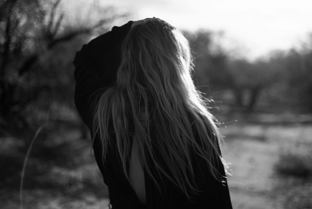 The art of softening - a woman walking away from the camera hand combing through her hair. 